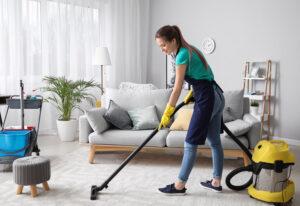 Reinigungskraft mit Staubsauger im Zimmer