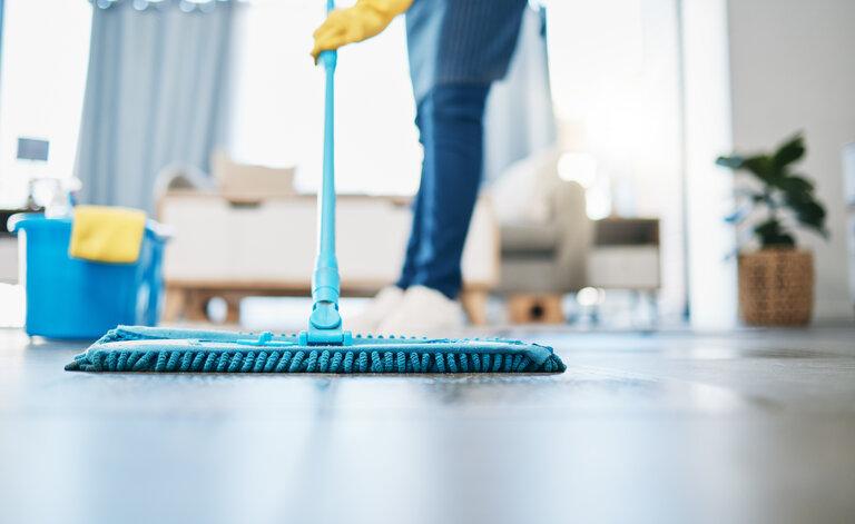 Dienstmädchen mit einem Mopp, um den Boden im Wohnzimmer in einem Haus zu reinigen.