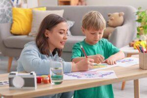 Kindermädchen mit kleinem Jungen beim Zeichnen zu Hause